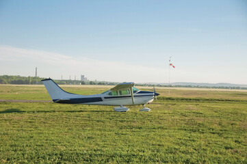 Fototapeta na wymiar Propeller plane parking at the airport and sky background. Small lightweight private airplane standing on airfield grass. Single prop aircraft on the ground. Airport in the field. Space for text.