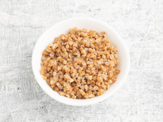 Buckwheat in ceramic bowl on white concrete background