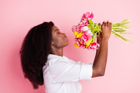 Profile photo of nice optimistic brunette hairdo lady hold flowers wear white shirt isolated on pink color background