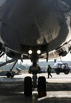 Jet's nose landing gear at the airport parking area. Aircraft service check before flight. 