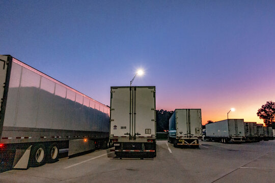 big rig semi trucks and trailers at rest area at sunrise