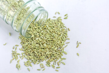 Dried organic fennel seeds or saunf in a glass jar on white isolated background.