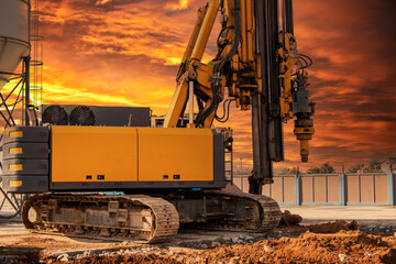 Hydraulic drilling rig against the backdrop of the sunset sky. Installation of bored piles by...