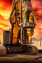 Fototapeta na wymiar Hydraulic drilling rig against the backdrop of the sunset sky. Installation of bored piles by drilling. Foundations and foundations. Drilling in the ground.