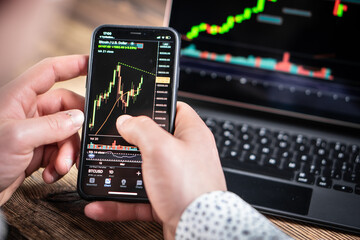 A man holds a phone in his hand and trades in cryptocurrencies on the stock exchange.
