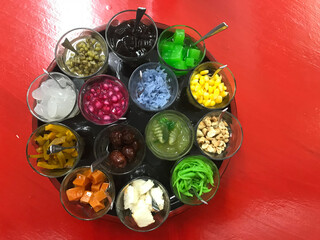 many kinds of sweet fruits for topping the Thai style ice cream which is in the tray on the red table