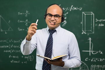 Teacher man holding chalk and teaching the mathematics in classroom.