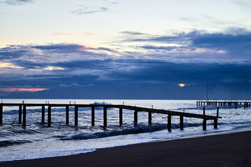 Obraz premium View from beach to water of sea, waves with white foam, pierce and sky with clouds in a nice evening.
