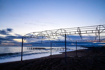 Fototapeta premium View from beach to water of sea, waves with white foam, pierce and sky with clouds in a nice evening.