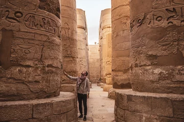 Foto op Plexiglas Young man gazing up in wonder at the massive columns at Karnak Temple in Luxor Egypt © Olivia