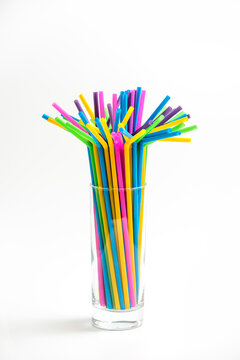 Multicolored Plastic Cocktail Straws In A Glass Tumble On White Background