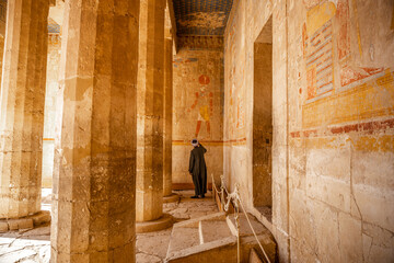 Traditionally dressed man gazing up at the Hieroglyphics in Hatshepsut temple in Luxor Egypt 