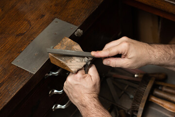 goldsmith sands a silver ring on the workbench.