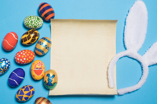 Beautiful Easter photo with eggs and bunny ears with parchment paper for text.on a light minimalist blue background.