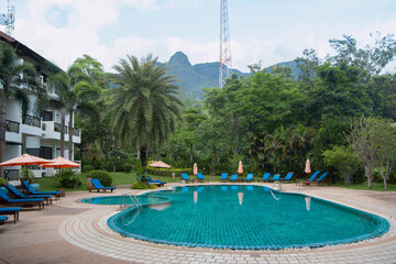 Deserted Thai hotel with a swimming pool, palm trees and sunbeds on a sunny day. Quarantine. Anti-COVID Restrictions