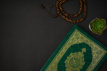 Holy Al Quran with written arabic calligraphy meaning of Al Quran and rosary beads or tasbih on...
