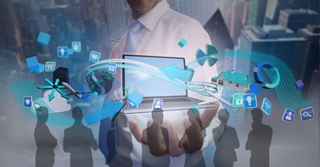 Composition of digital icons over businessman holding laptop and silhouettes of business people