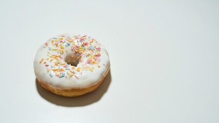 Unhealthy desserts that you must avoid. Freshly baked delicious donut with colorful sprinkles and white sugar glaze isolated on light background