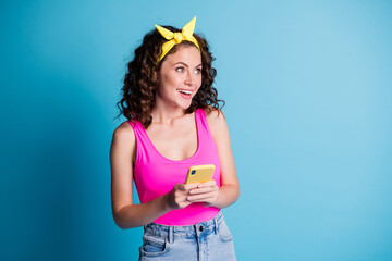 Photo of young attractive woman happy smile dream look empty space hold cellphone isolated over blue color background