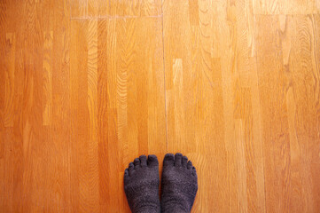 フローリングの上の5本指の靴下を履いた足。