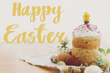 Happy Easter text on delicious homemade Easter bread, stylish easter eggs, blooming spring flowers on rustic table, handwritten sign. Beautiful stylish greeting card. Seasons greetings © sonyachny