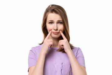 Fototapeta premium close up girl tries to pull a smile with fingers over her mouth and forcing himself cheerful. Fake smile concept