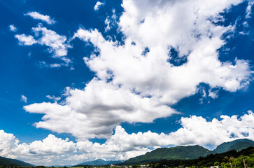 Rolling mountains with blue sky and clouds background.