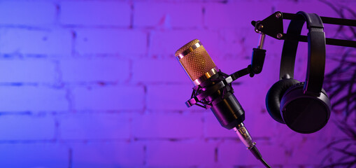 stand with microphone and headphones on brick wall background. online radio and podcasting concept....