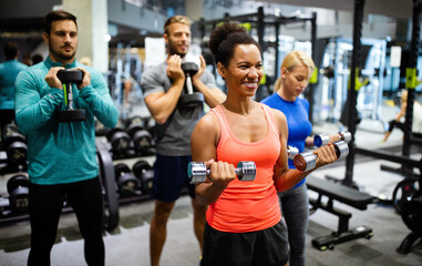 Group of young happy fit people doing exercises in gym