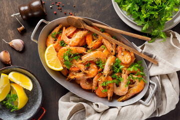 Roasted shrimps with garlic, lemon and parsley, black background, top view, copy space