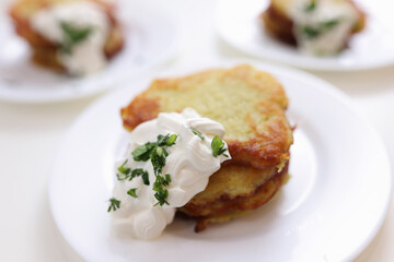 Potato pancakes in sour cream sauce lying on white plate