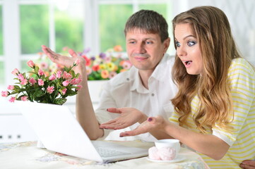young couple sitting at table and using laptop
