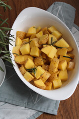 Raw Potatoes ready to be baked with rosemary and olive oil. Preparing roasted potatoes with spices over withe baking dish. 