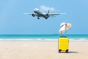 Summer traveling and planning with yellow suitcase luggage with big white hat fashion on the sand beach. Travel in the holiday, airplane 