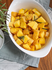 Raw Potatoes ready to be baked with rosemary and olive oil. Preparing roasted potatoes with spices over withe baking dish. 