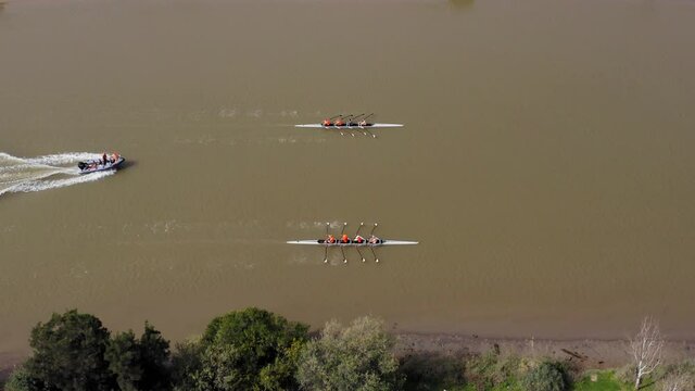 Two Sport Canoes with a team of four people rowing on tranquil water, Aerial view.