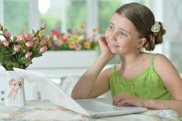 Obraz na płótnie Canvas happy cute girl using laptop at home