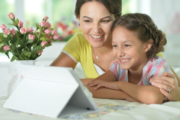 happy mother and daughter using tablet together at home