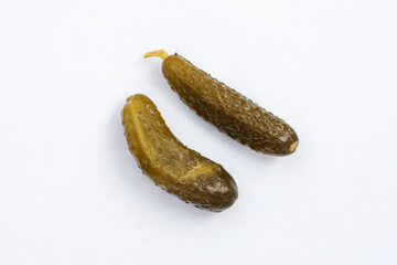 Two pickled cucumbers, isolated on a light background, are salted in a barrel. Top view