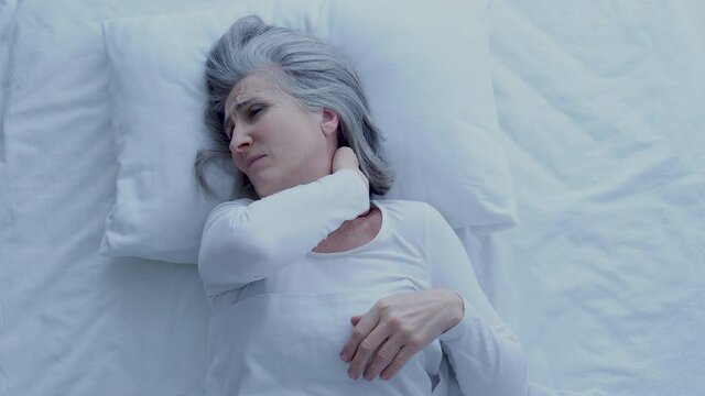 Female feeling neck pain, lying on uncomfortable mattress and pillow, health
