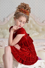 cute little  girl in red dress sitting in bedroom