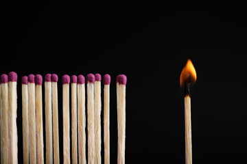 Burning match among others on black background