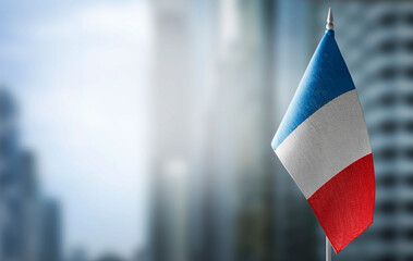 A small flag of France on the background of a blurred background