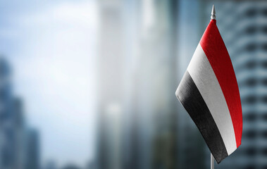 A small flag of Yemen on the background of a blurred background - obrazy, fototapety, plakaty