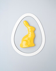 Yellow rabbit in white frame on a gray background. Minimal Easter story.