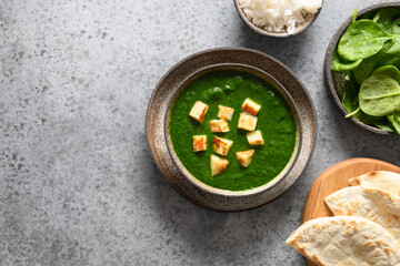 Fototapeta na wymiar Palak Paneer served with basmati rice on grey stone background. Indian vegetarian cuisine made of spinach and paneer cheese. Copy space. View from above.