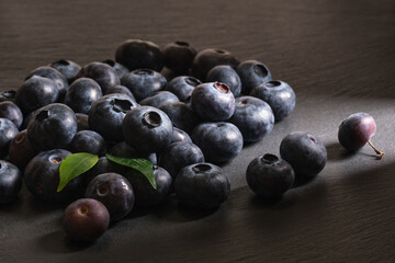 Fresh blueberries are scattered on a dark stone background. Products for a healthy diet. A source of vitamins. 