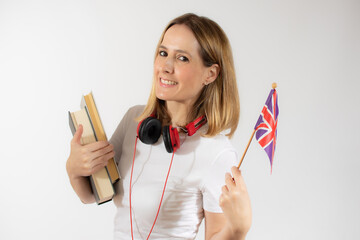 Portrait of a smiling casual young woman with backpack holding books and british flag isolated over white background