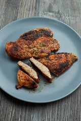 fried chicken breast lies on a plate. one breast is slightly cut into pieces.