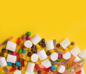 A lot of sweets jelly, marmalade, peanuts, chocolate. On a yellow background. Copy space